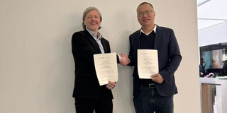 Auf dem Bild sind Prof. Dr. Chris Neuhäuser, Professor für Praktische Philosophie am Institut für Philosophie und Politikwissenschaften der Fakultät Humanwissenschaften und Theologie und Prof. Dr. Wang Jun, der Leiter der School of Philosophy, zu sehen. Beide halten das Memorandum in der einen Hand und reichen sich die andere Hand. Beide lächeln.