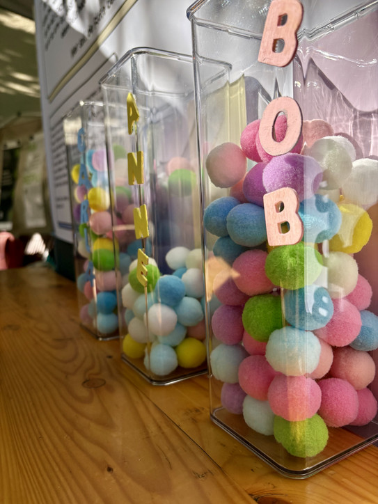 Auf dem Bild sind drei Glassäulen mit bunte Stoffbällchen darin.