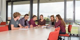 Studierende sitzen mit Lernunterlagen am Tisch.